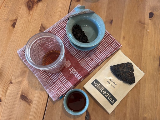 Tea in a gaiwan, a cup, and a mason jar. A bag labeled “2022 Fleet, 25g, white2tea” has a chunk of dry tea leaves sitting on top 