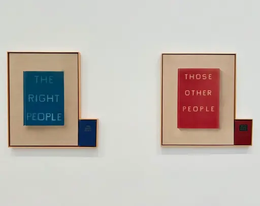 Two paintings are placed together on a wall. One painting is of a blue book titled The Right People, and the other is a red book titled Those Other People. Beside each painting are physical hardcover books that look like the ones in the paintings. The frame of each painting is extended so that the books are framed within the same frame as the paintings. 